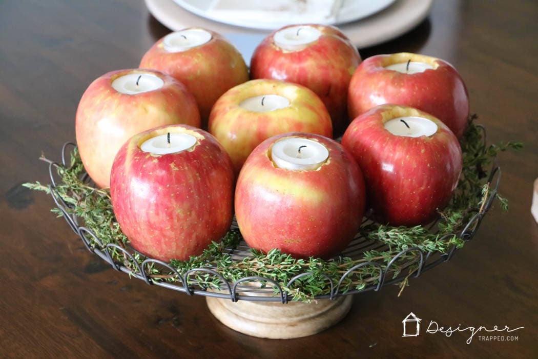 fresh herbs surrounding fresh apples turned into tealight candle holders in table centerpiece
