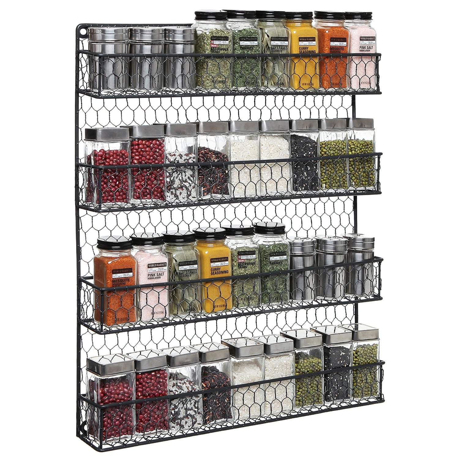 A chicken wire hanging spice rack full of varying spices, both ground and unground against a white background.