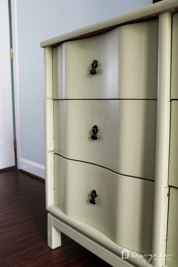 A close-up of chipping latex paint on a three drawer vintage dresser. Learning how to paint wooden furniture will prevent paint from looking dirty and tattered later on.