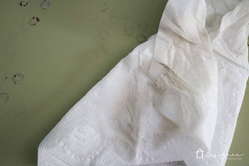 Residue and dirt on a paper towel on a dull green surface is visible confirmation that Simple Green cleaner works and is a crucial step on how to paint wood furniture.