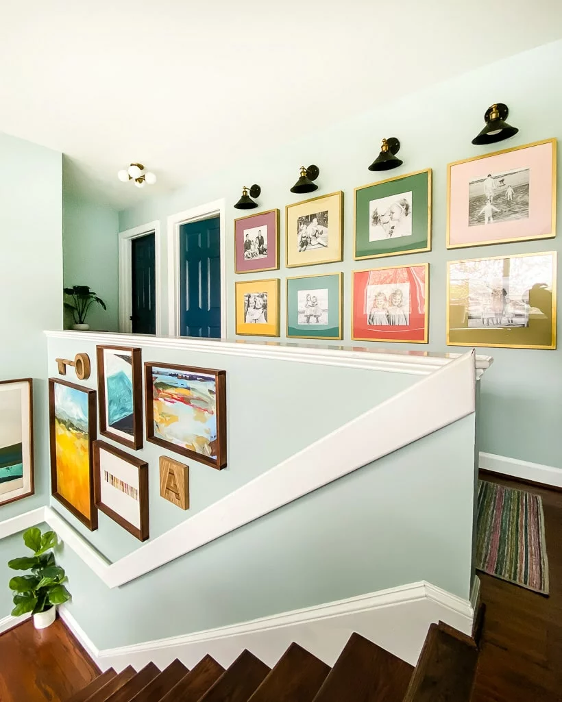 colorful art and gallery wall on stairs with flat modern white bannister