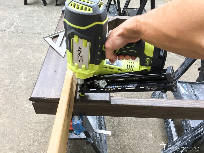 nail gun attaching horizontal slats to DIY utility box cover