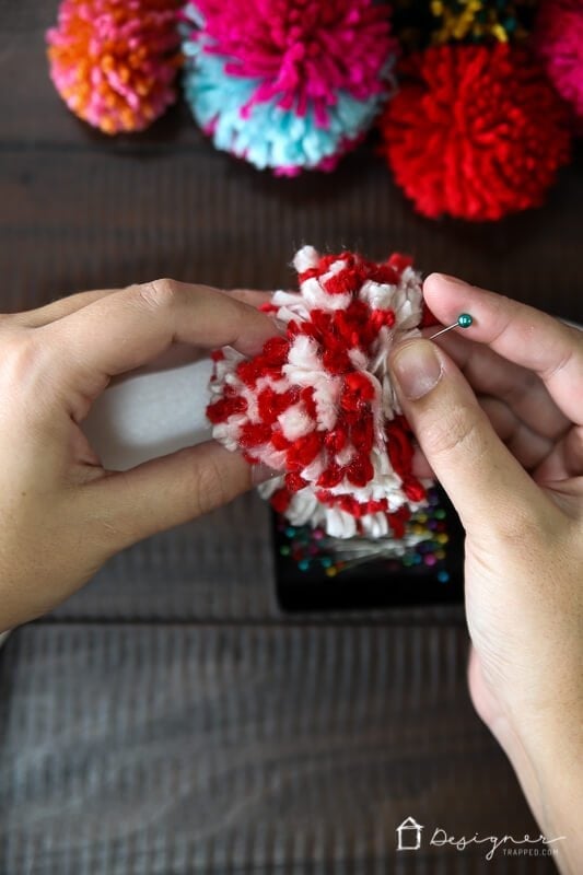 pinning pom poms on diy pom pom wreath by Tasha Agruso of Kaleidoscope Living