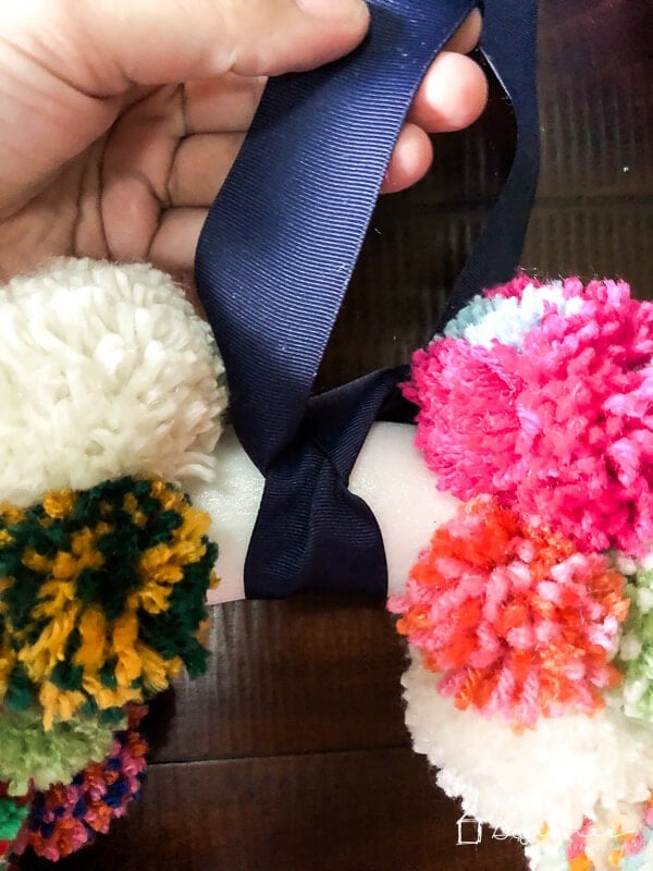 tying ribbon on diy pom pom wreath by Tasha Agruso of Kaleidoscope Living