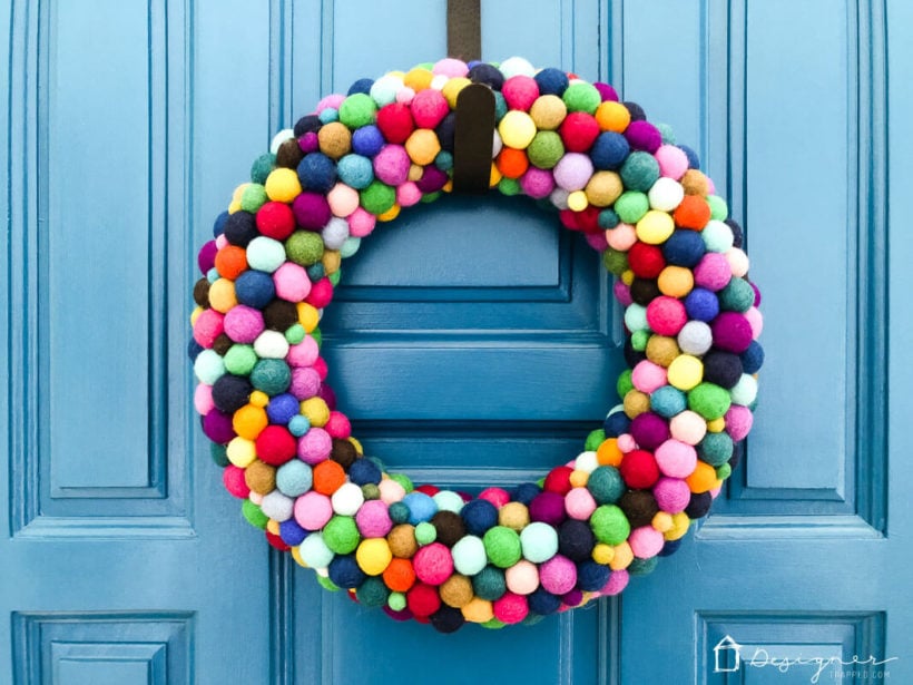 finished colorful diy felt ball wreath hanging on blue door