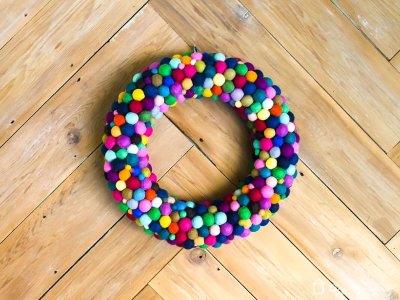 finished colorful diy felt ball wreath hanging on wood wall