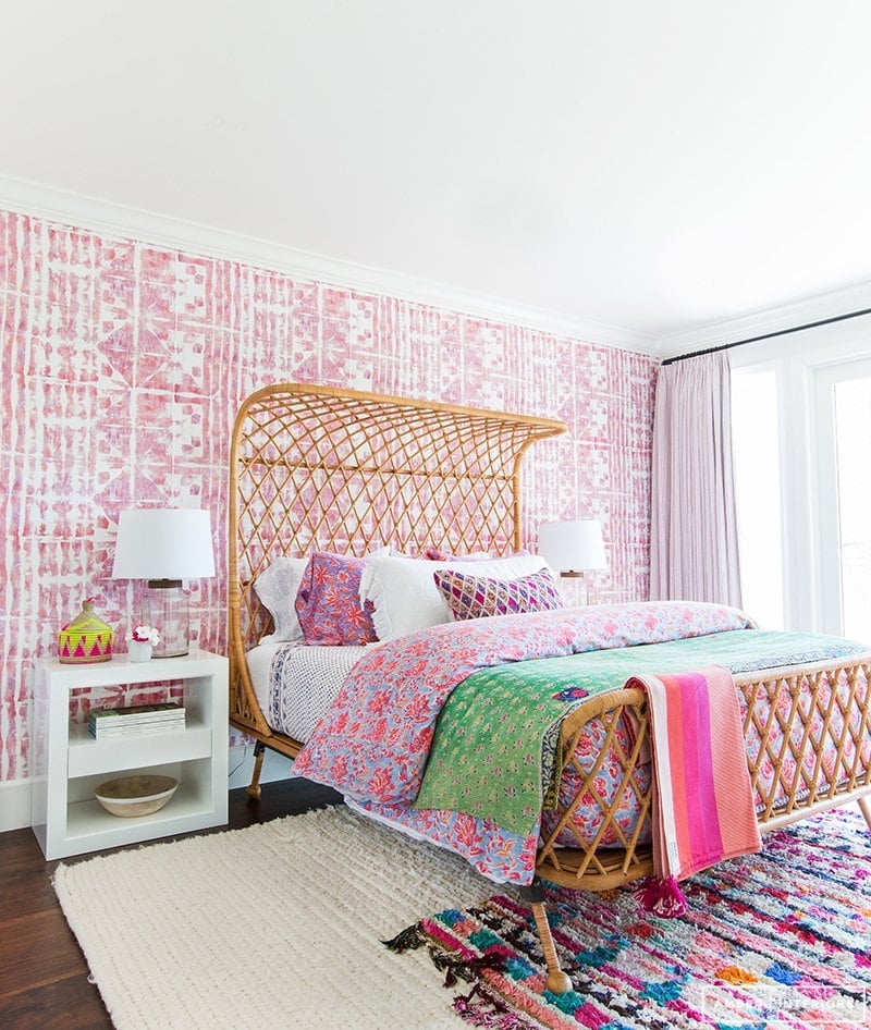 eclectic boho girl's bedroom with rattan bed, pink and white batik wallpaper and pink and green bedding