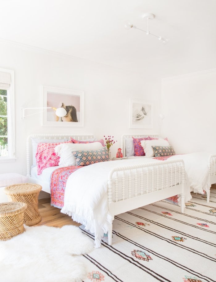 minimal shared bedroom with two double beds with white bedspreads and bright pops of pink