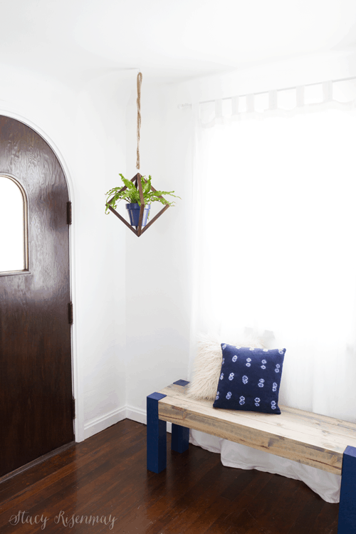 white entryway with arched door and bench with bright blue legs