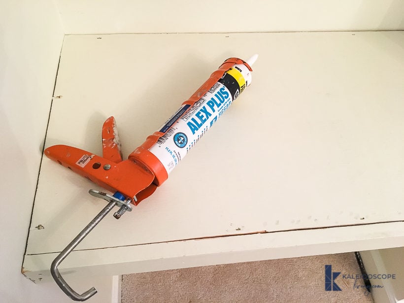 caulk and caulk gun on shelf