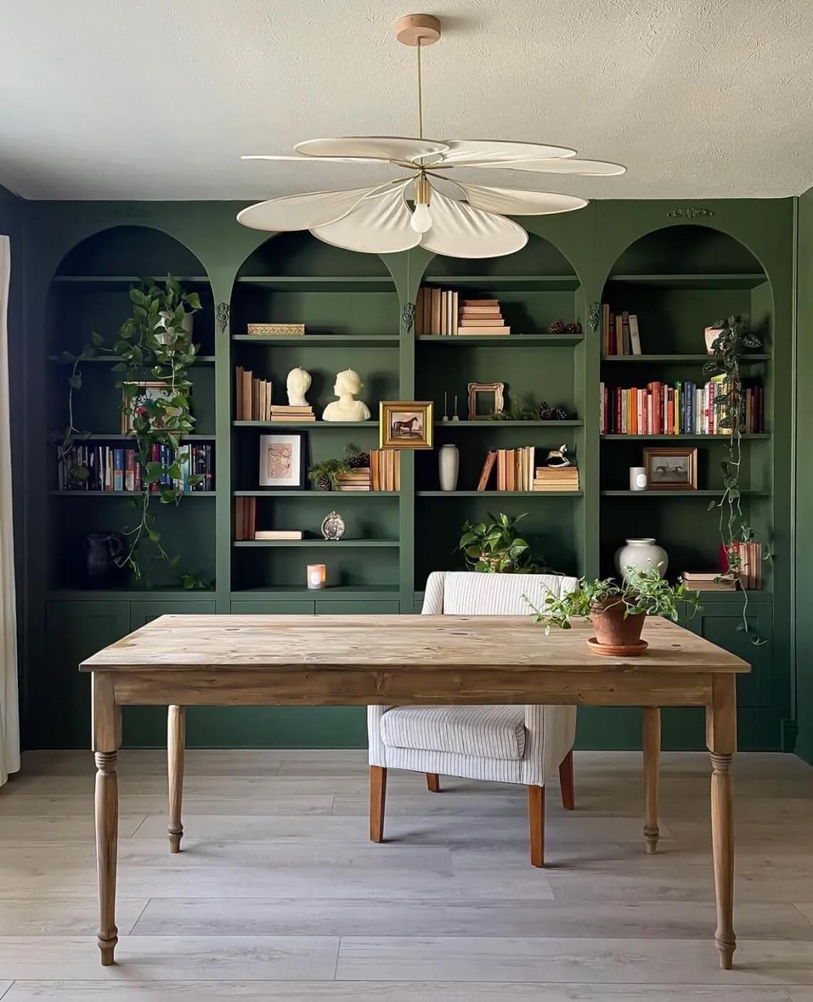 Green IKEA office bookcases take up the whole wall behind the desk. Arches have been added to the bookcase to make them look like built-ins.