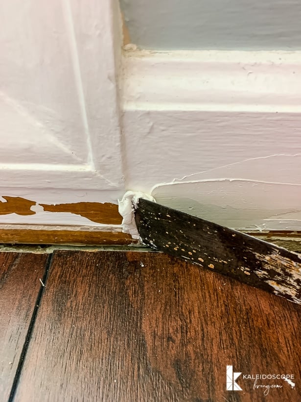 applying DAP Alex Plus Spackling to a damaged baseboard