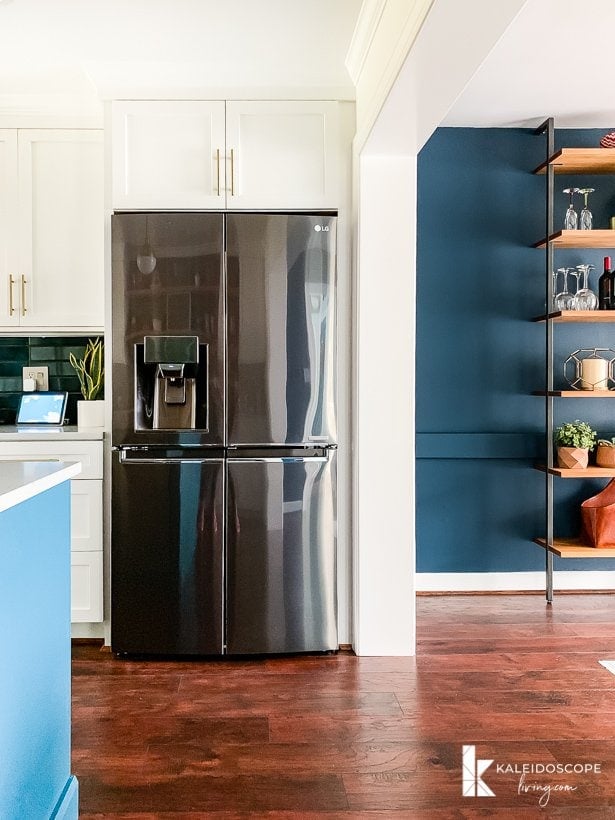 white and teal kitchen open to navy blue dining room