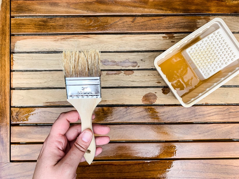 applying teak oil to outdoor table