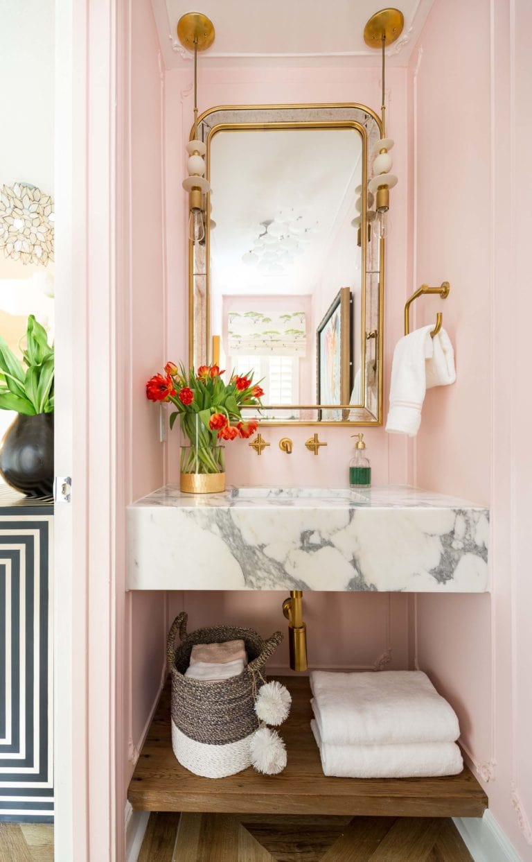 pink powder room with eclectic gold lighting and fixtures and marble sink