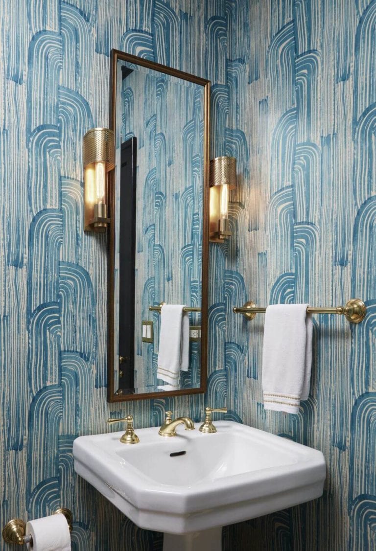 blue abstract print wallpaper with long narrow mirror and gold fixtures