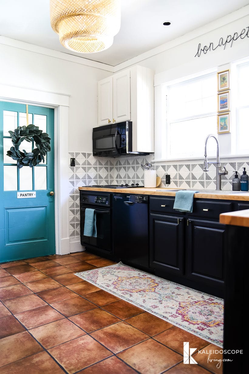 kitchen with terra cotta floors, black and white cabinets, and turquoise accents