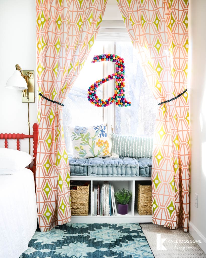 reading bench with cushions and storage underneath, framed by geometric print curtains