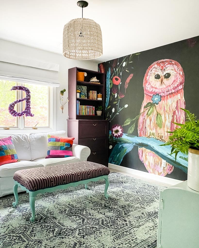 colorful owl mural accent wall with eggplant bookshelves and IKEA loveseat