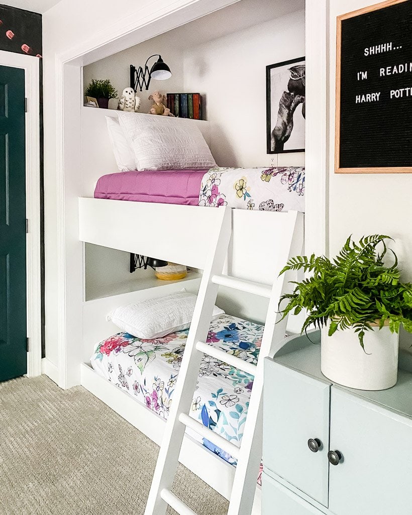 built-in bunk bed in closet with floral bedspreads and shelves