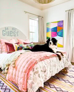 guest room with floral bedspread, bright abstract art and large dog on bed