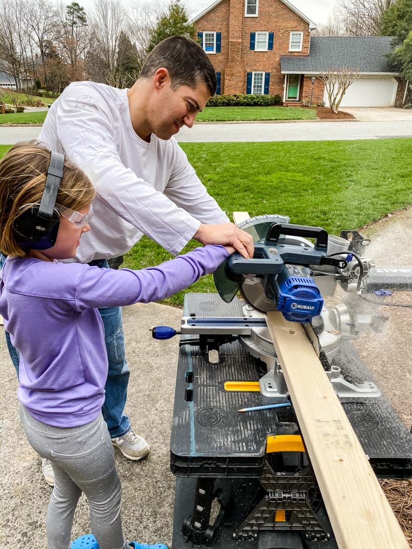 father and daughter using saw together