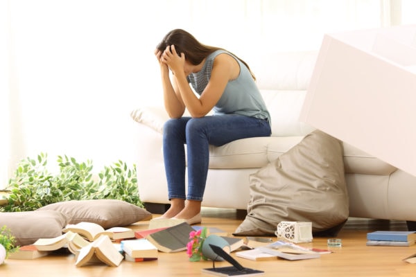 woman with head in hands in disorganized room