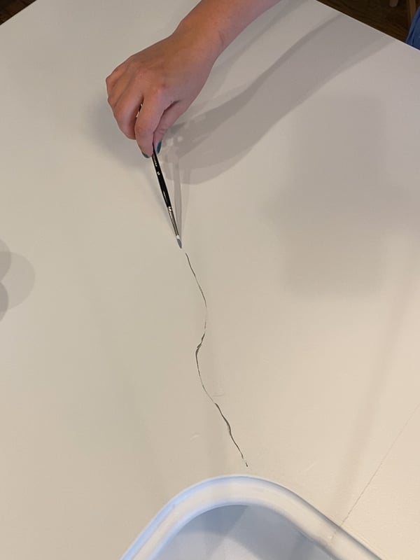 photo of woman painting grey veins on countertops to look like marble