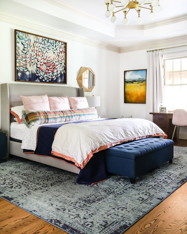 Colorful bedroom with large art and navy bedding.