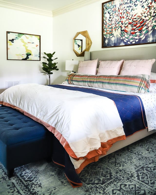 colorful bedroom with white bedding, pink pillows and plaid lumbar pillow