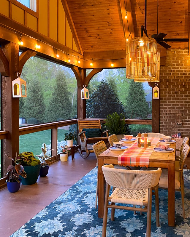 screened-in-porch outdoor dining table with rug underneath