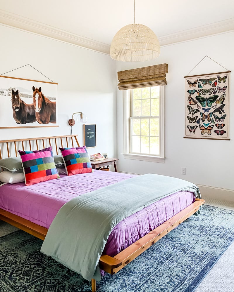 girls bedroom with mid century low wood bed with purple and sage bedding and naturalist prints on walls