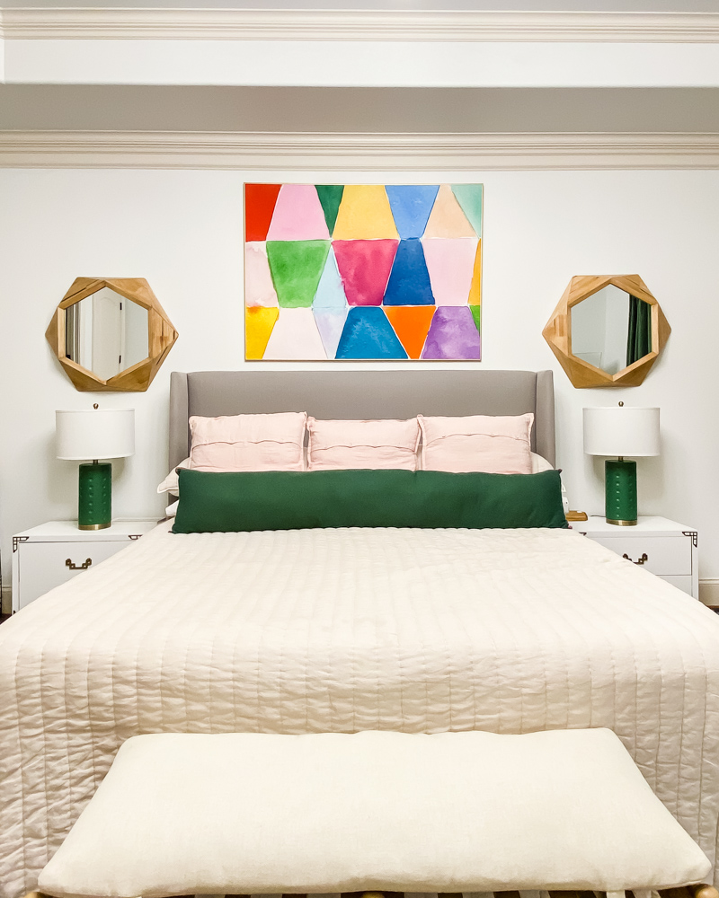 bedroom with colorful art, lamps, and bedding and white bedside tables