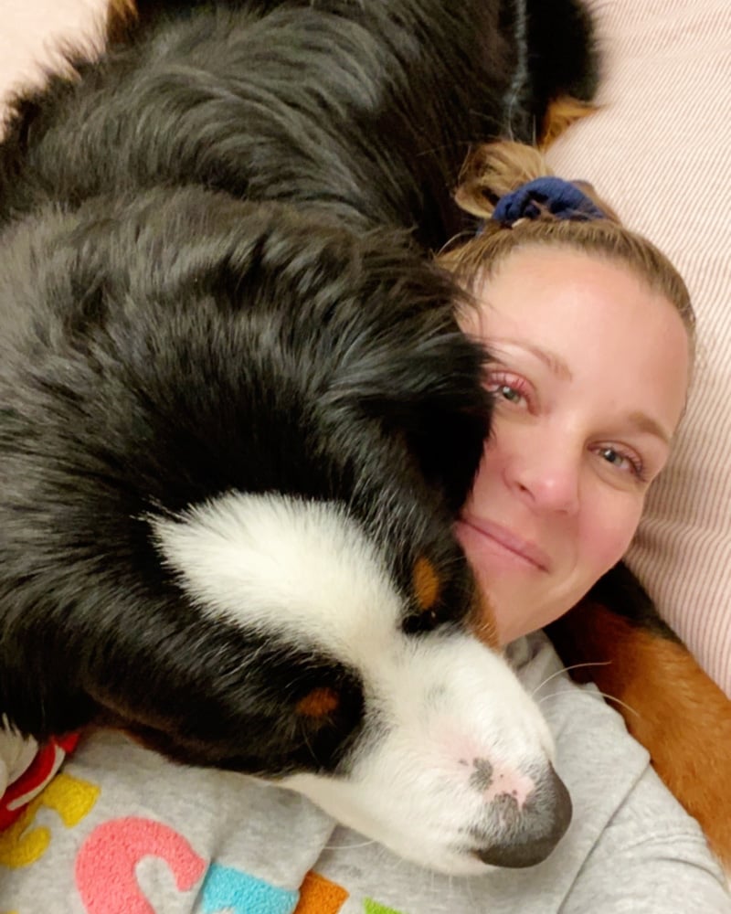 woman snuggling Bernese Mountain Dog