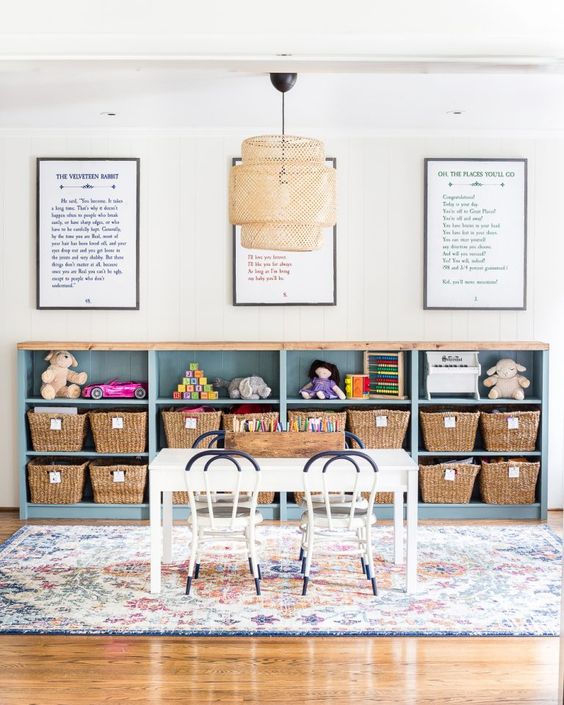 IKEA's short Billy bookcases are against the back wall of a playroom. Framed messages are above the storage wall, and a children's table is in front. This DIY IKEA hack provides loads of playroom storage. 