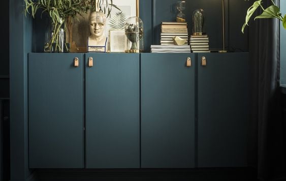 Dark green built-ins against a dark green wall, made from IKEA Ivar cabinets. Books, plants, and art adorn the credenza. 