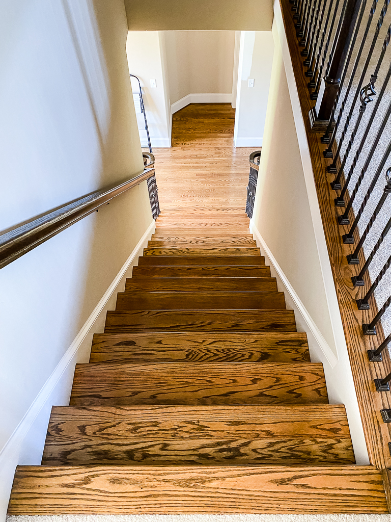 beige staircase with iron balusters and wood floors