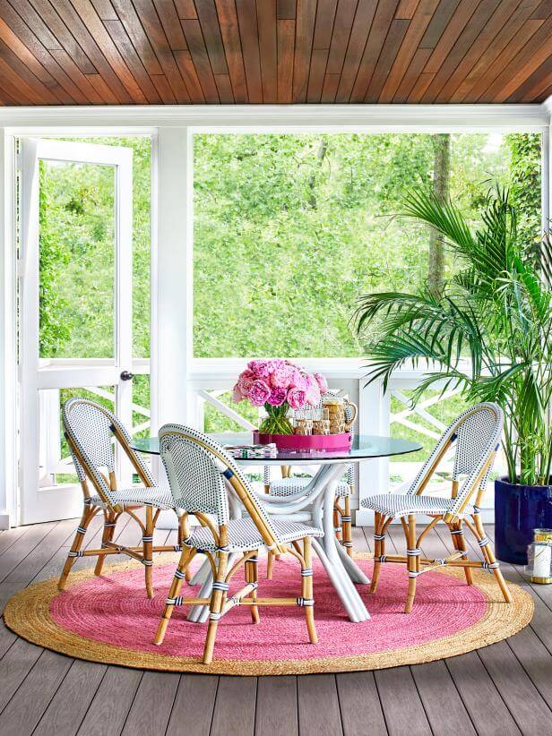 screened-in porch with round table and pink rug 