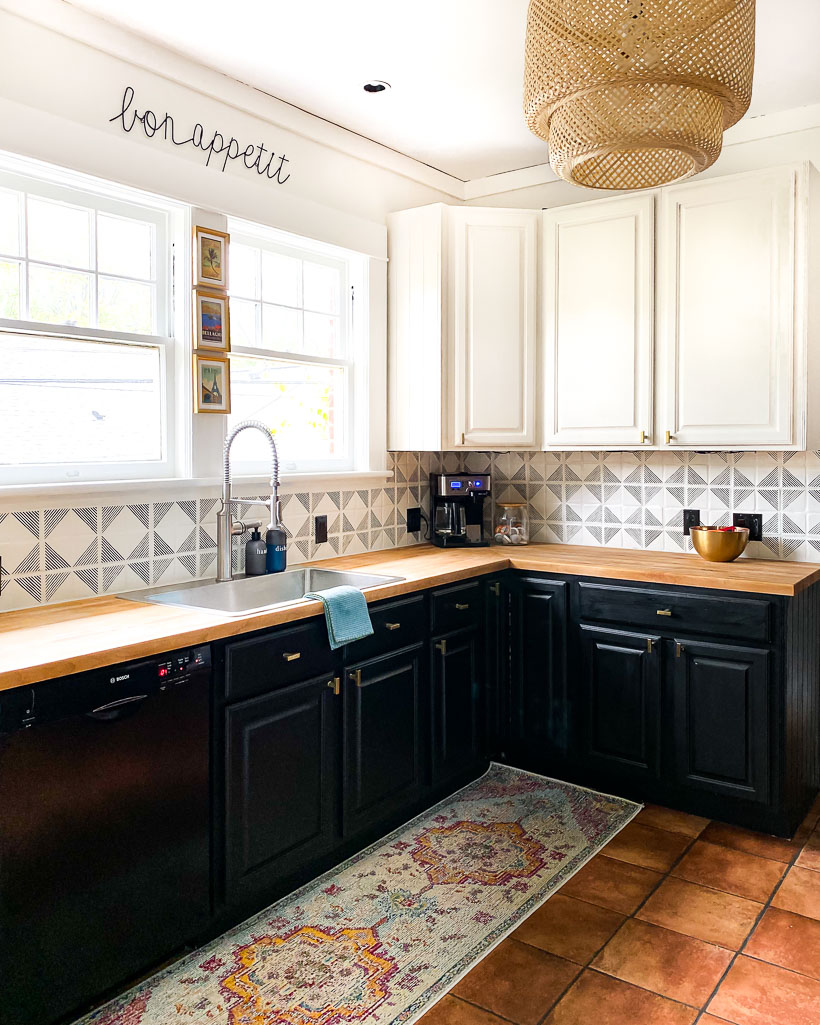 stenciled backsplash with black cabinets and terra cotta tiles