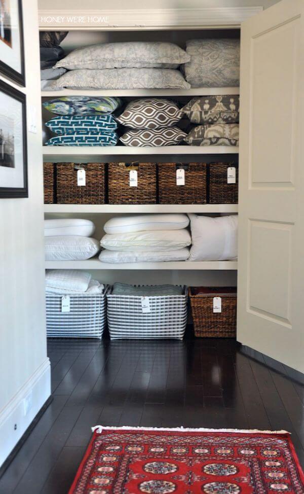 organized hall linen closet with hanging label tags on baskets