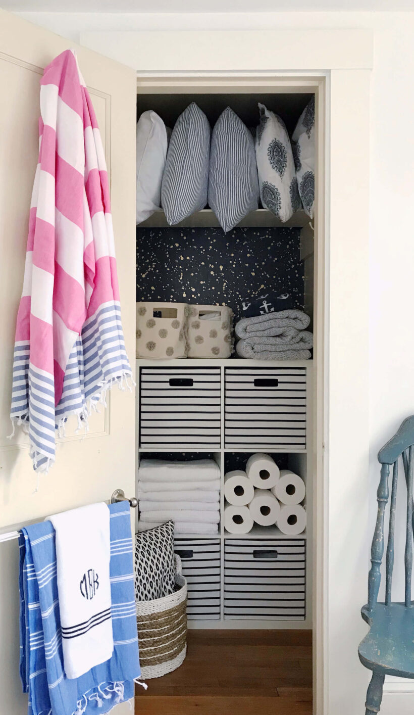 linen closet with wallpaper and shelf unit for organization