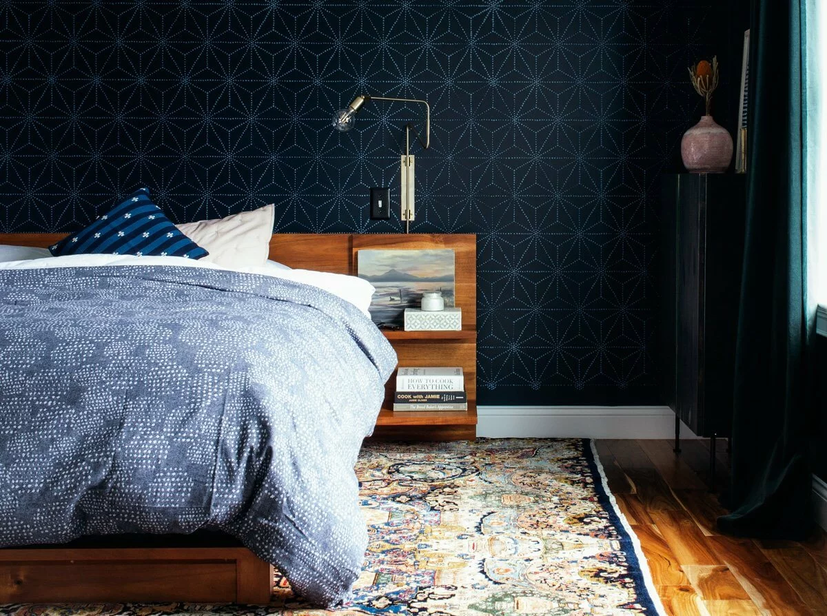 Polo Blue bedroom walls with a geometric print behind a bed with a light blue bedspread. 