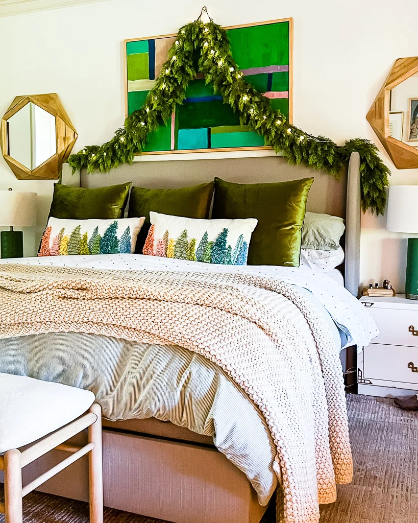 realistic artificial garlands hanging over bed in bedroom decorated for Christmas