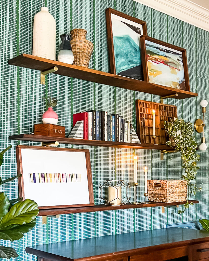 DIY wall shelves styled with books and art hanging. on green and white wall