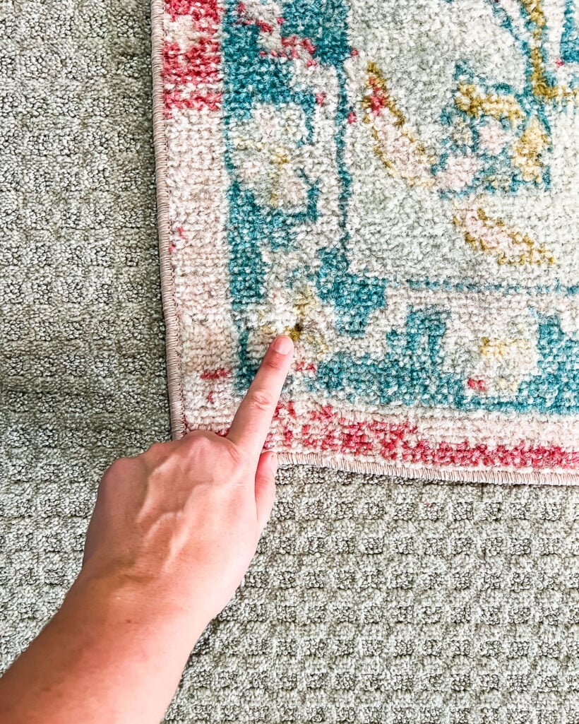 screw in corner of area rug over carpet to keep it in place