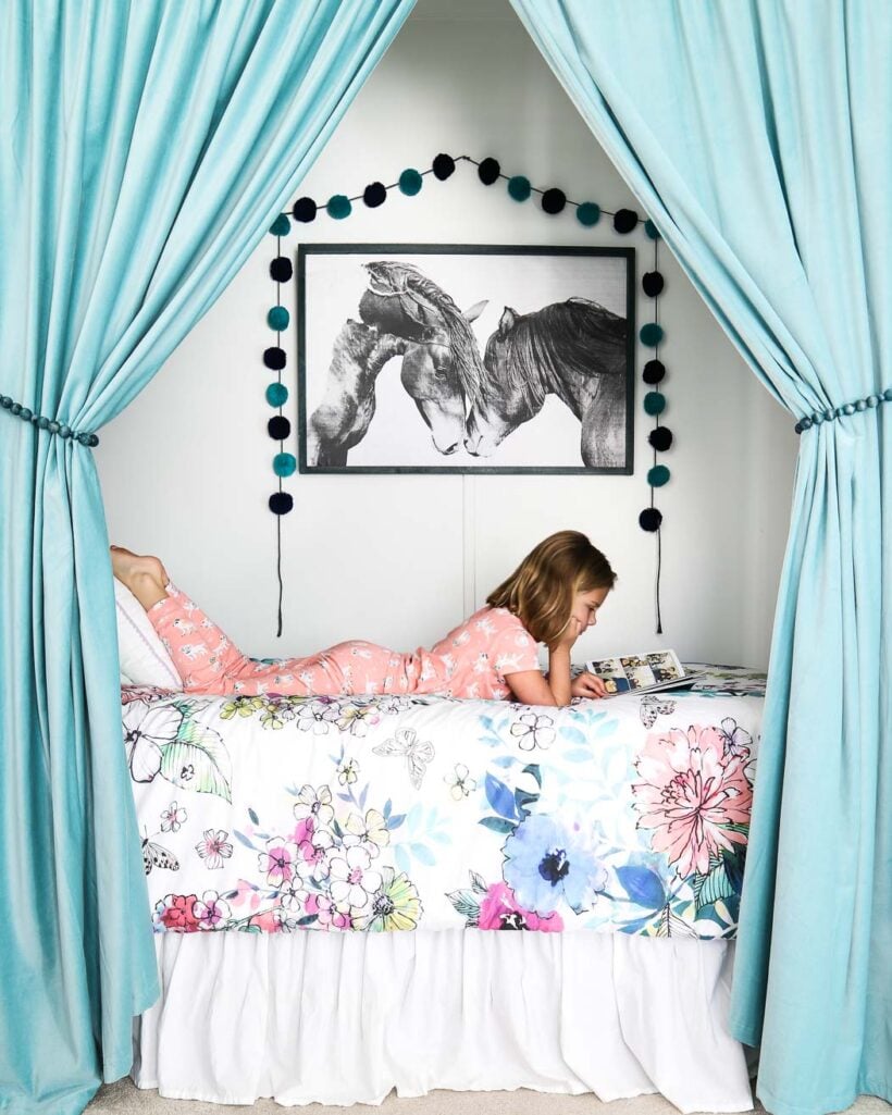 bed in closet framed by curtains in colorful girl's bedroom