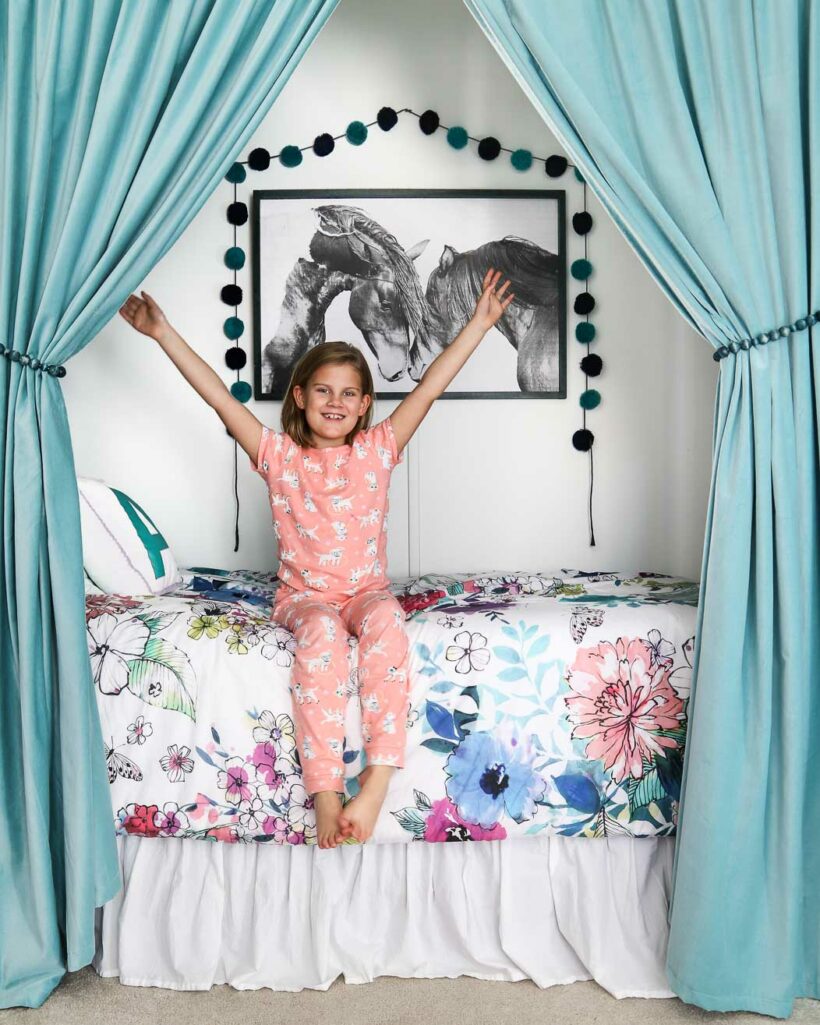 happy girl in bed nook in closet with curtains 