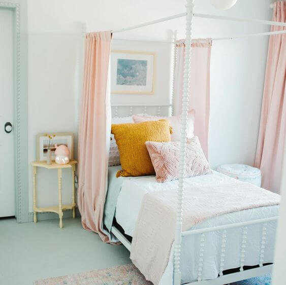 white canopy bed with pink curtains, pin and white bedding and mint sheets in girl's bedroom