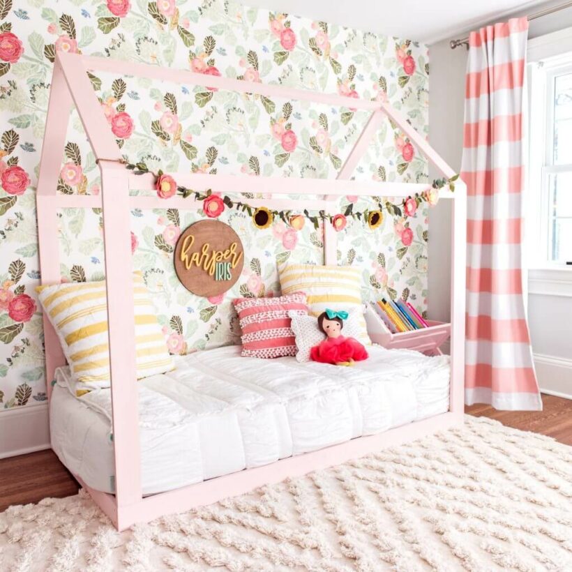 pink girls room with toodler house bed on floor and floral wallpaper