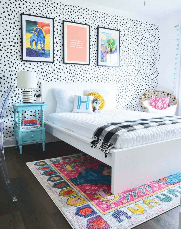 teen girl bedroom with black and white polka dot wallpaper, bright art, and white bedding